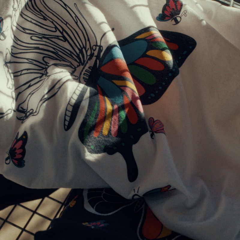 White tee with a rainbow butterfly print laid in a cart